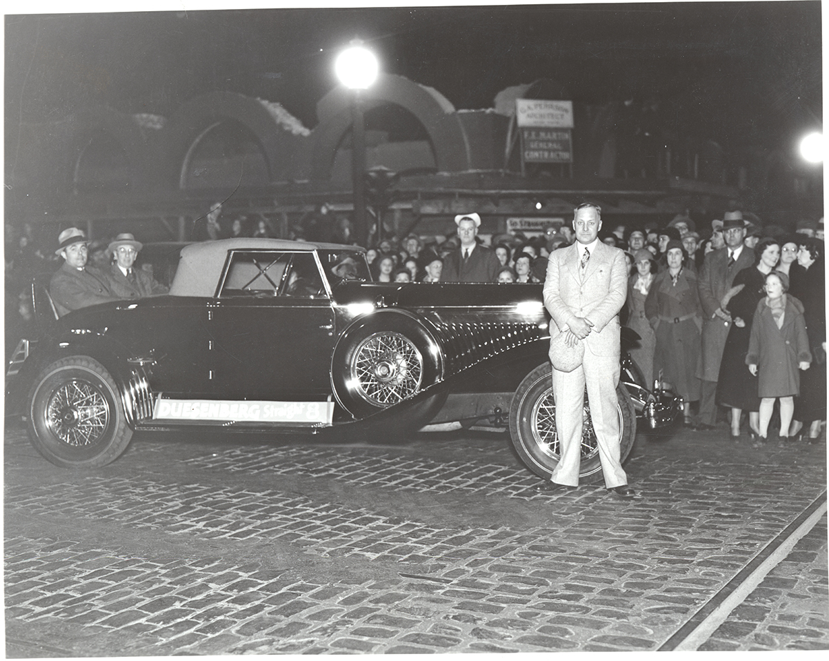 Photograph of Frank B. Robinson beside his Duesenberg Convertible Coupe in front of crowd
